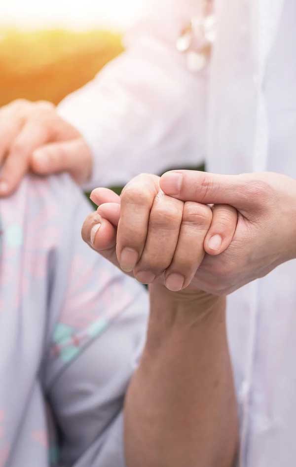 closeup of person offering comfort by holding hands